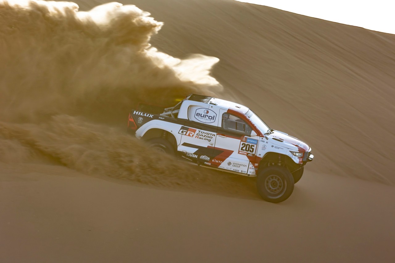 Hilux profile shot blistering through desert kicking up sand