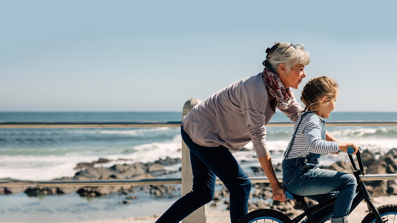 Dynamic grandmother helping grandchild to ride her bicycle